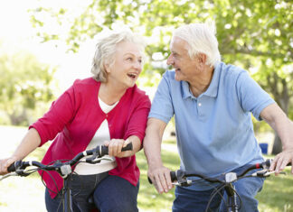 Aktywność fizyczna osób starszych - para uśmiechniętych seniorów podczas jazdy na rowerach