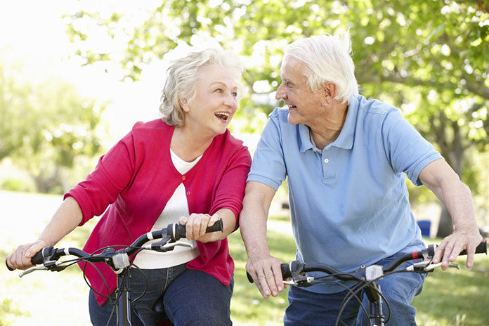 Aktywność fizyczna osób starszych - para uśmiechniętych seniorów podczas jazdy na rowerach